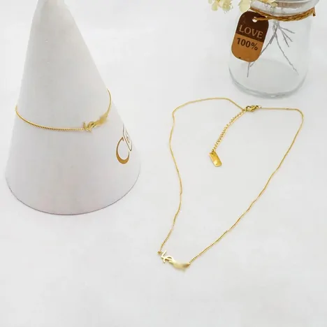 Two fine gold chain necklaces, one draped over a white cone stand