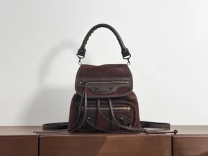 A brown leather backpack with a top handle on a counter